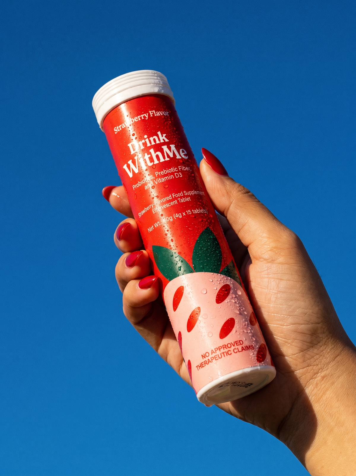 A hand holding up the Drink WithMe Strawberry tube against a blue sky